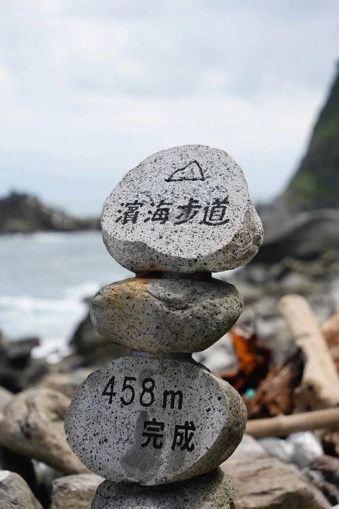 寫有濱海步道與 458 公尺完成字樣的疊石