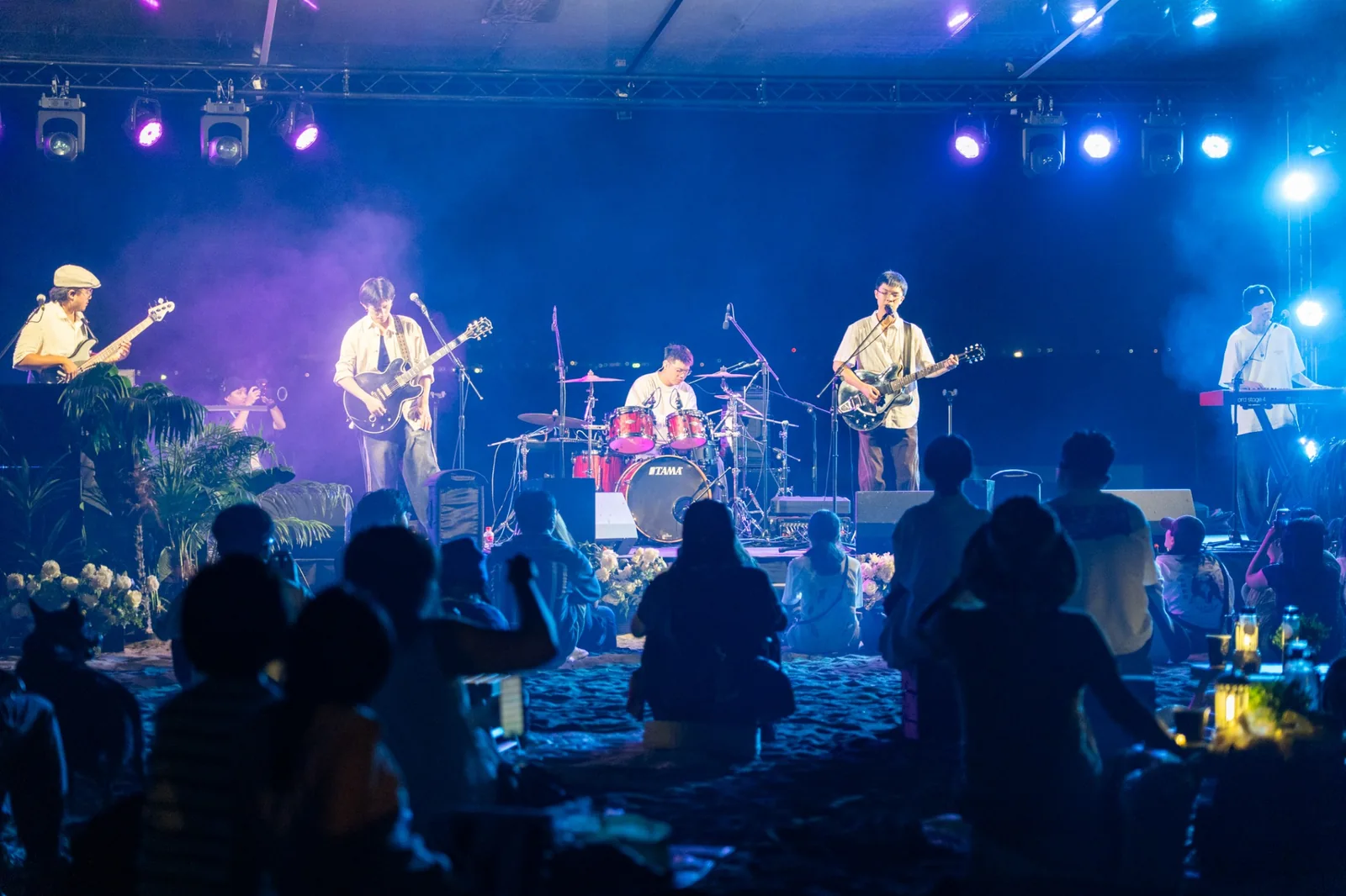 樂團在夜間水岸舞台演出,觀眾隨著音樂互動